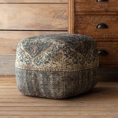 a foot stool sitting on top of a wooden floor next to a dresser and drawers