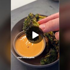 a person dipping sauce into a bowl of broccoli