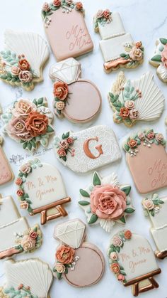 wedding cookies decorated with flowers and seashells on a marble table top for a bridal party