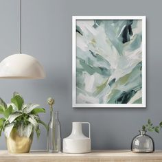 an abstract painting hangs on the wall above a wooden table with vases and plants