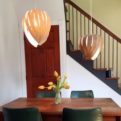 a wooden table topped with green chairs next to a bannister and stair case