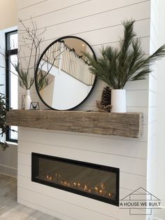 a white fireplace with a mirror above it and a black cat sitting on the mantle