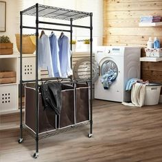 an ironing rack with clothes hanging on it in a laundry room next to a washer and dryer