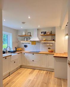 an open kitchen with white cabinets and wood flooring is seen from the doorway to the dining room