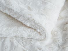 a white blanket is folded up on top of a bedding with an intricate pattern