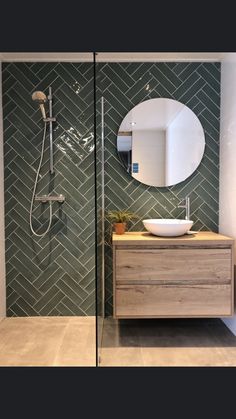 an image of a bathroom with green tiles on the walls and wood vanity in the middle