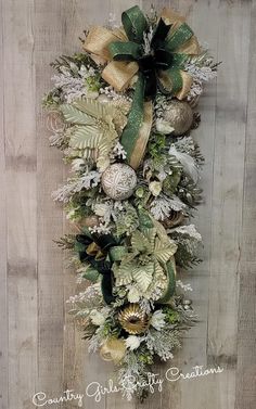 a christmas wreath hanging on the side of a wooden wall with green and gold decorations