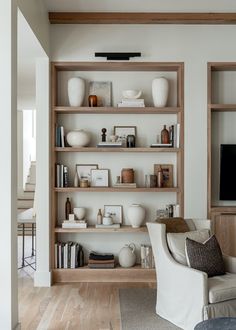 a white room with shelves filled with books and vases