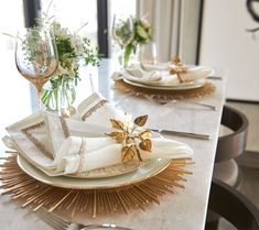 the table is set with white and gold plates, napkins, and silverware