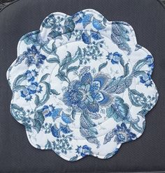 a blue and white plate sitting on top of a piece of cloth covered in flowers