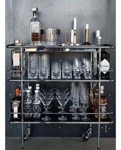 a metal bar cart filled with glasses and liquor bottles on top of eachother