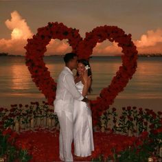 a man and woman standing next to each other in front of a heart shaped frame