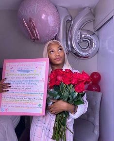 a woman holding flowers and a sign in front of balloons