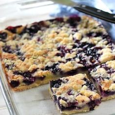 blueberry crumb bars cut into squares and placed on a baking sheet with a serving utensil