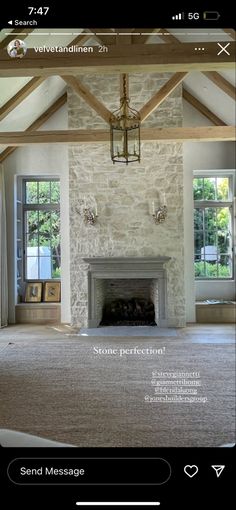 an image of a living room with stone fireplace and large carpeted floor to ceiling windows