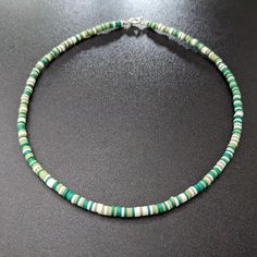 This lovely necklace is made with tiny 4mm polymer clay heishi beads and stainless steel wire. Necklace length is approximately 16 inches. Colors include shades of green and white. To extend the life of your necklace, avoid contact with sweat, lotions, and other chemicals. Please message me with any questions. To see other jewelry options, check out my full store: https://www.etsy.com/shop/shopcraftyoctopus/ Green Heishi Beads Round Necklace, Green Heishi Beads Necklace With Round Beads, Green Heishi Bead Round Necklaces, Green Tiny Heishi Beads Necklaces, Green Heishi Beads Necklace For Gift, Green Heishi Beads Round Beaded Necklace, Green Heishi Beads Jewelry For Beach, Adjustable Green Beaded Necklaces With Letter Beads, Adjustable Green Beaded Necklace With Letter Beads