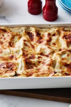 a casserole dish with cheese and sauce in it on a table next to plates