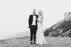 a man and woman standing on top of a hill