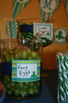 a glass filled with green olives sitting on top of a table next to candy