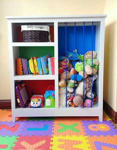 a white bookcase filled with lots of toys on top of a colorful carpeted floor