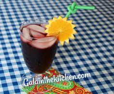 a drink sitting on top of a blue and white checkered tablecloth with an orange garnish