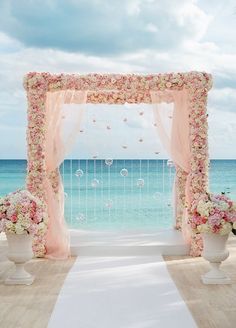 an outdoor wedding ceremony setup with flowers and petals on the aisle, overlooking the ocean