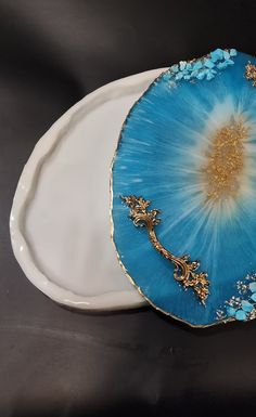 a blue and gold plate sitting on top of a white platter next to a black table