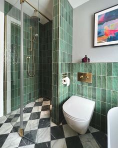 a green tiled bathroom with a white toilet and stand up shower in front of a black and white checkered floor