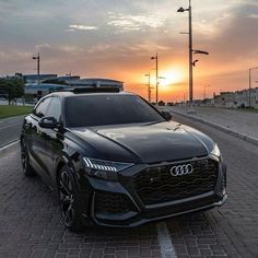 a black car is parked on the side of the road in front of an orange sunset