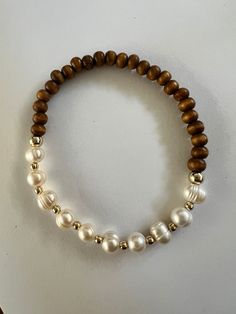 New style just added to our line up. Beautiful genuine pearl with wood and gold plated beads. The classic combination is perfect for dressing up or down. Perfect for everyday wear, the bride to be or your festival fashion. Made with high quality stretch string, size 7. It is recommended to remove before swimming or showering. Wood beads are not colorfast. Wood Bead Bracelet, Wood Bracelet, Gold Bead Bracelets, Diy Bracelet Designs, Layered Bracelets, Bracelet Stack, Gold Beads, Jewelry Projects, Pearl Bracelet