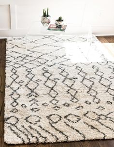 a living room area with a rug, coffee table and potted plants on the floor