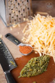 a cutting board topped with cheese next to a knife and grated parmesan cheese