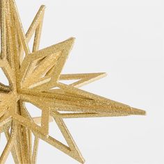 a gold glittered star ornament against a white background