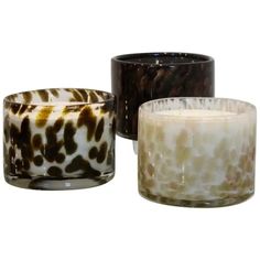 three glass candles sitting next to each other on a white surface with brown and black spots