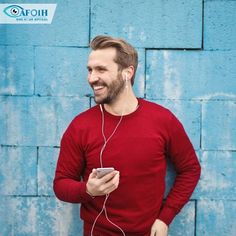 a man standing in front of a blue wall wearing headphones and listening to music