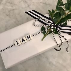 a gift wrapped in black and white ribbon with the word italian written on it next to a plant