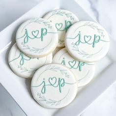 four decorated cookies sitting on top of a white plate with the word love spelled in green