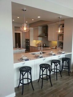 a kitchen with three bar stools next to an island in the middle of it