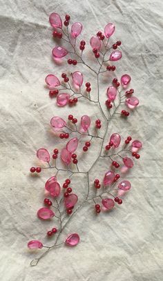 some pink flowers and red berries on a white sheet