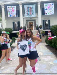 two girls are standing in front of a house holding up signs that say i love my mom