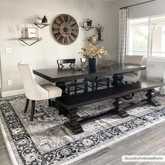 a dining room table with chairs and a clock on the wall