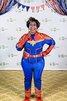 a woman dressed as captain america standing in front of a backdrop