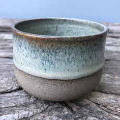 two bowls sitting on top of a wooden table next to each other, one blue and the other gray