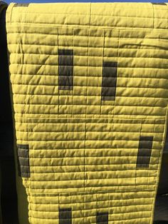 a yellow quilt with black squares on it