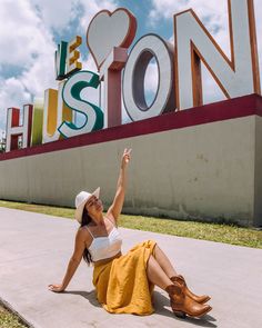 a woman sitting on the ground in front of a sign that says i love houston