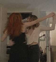 two young women are dancing in the kitchen, one has her arms around the other