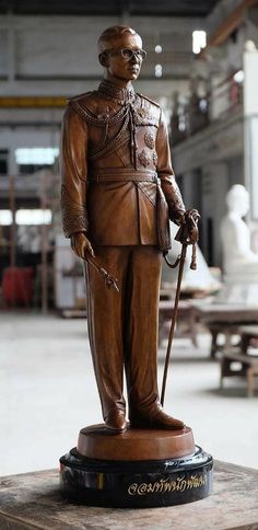 a statue of a man holding a cane and wearing a suit, standing in a warehouse