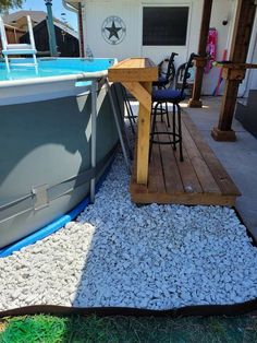 a boat sitting on top of a wooden deck next to a swimming pool with chairs