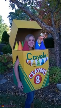 a girl in a crayon 8 costume holding a cardboard box on her head