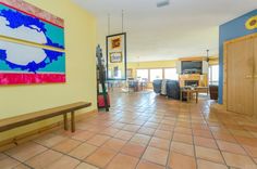 an open living room and dining area with tile flooring, yellow walls and blue accents